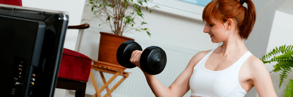 image of a healthy hack of woman lifting weights while watching tv