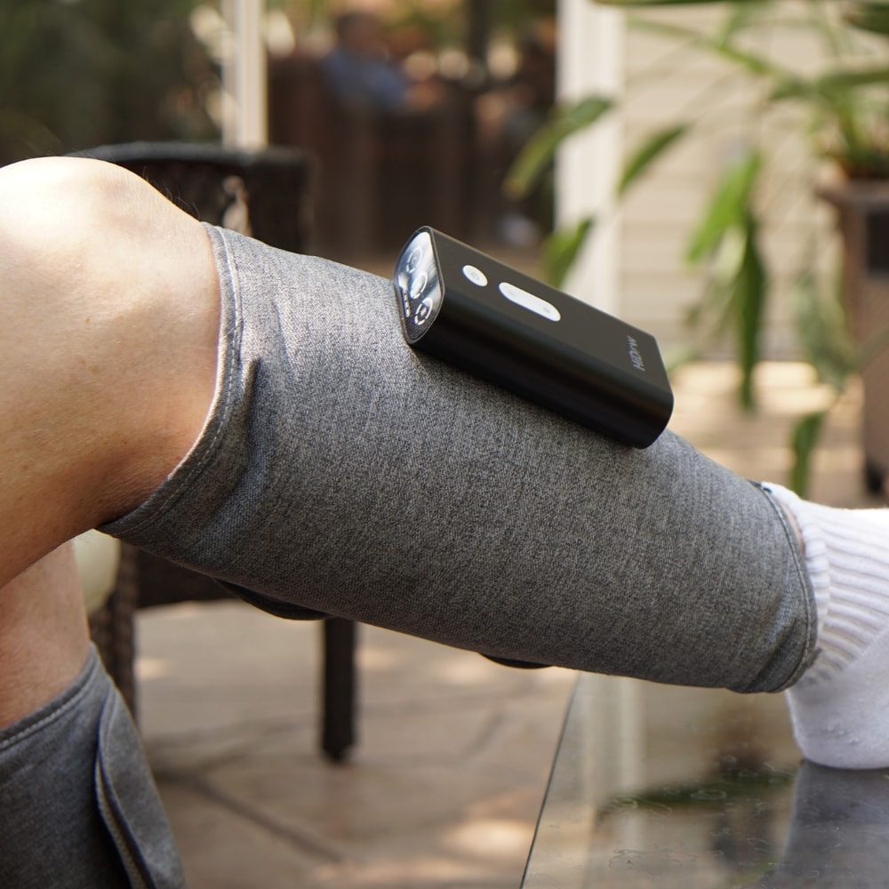 Man relaxing outdoors with HiDow ThermoAir Wave Leg Compression Wraps.